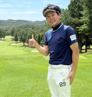 89の数字の入ったパンツを履いてゴルフ場でポーズをとる重田さんの写真