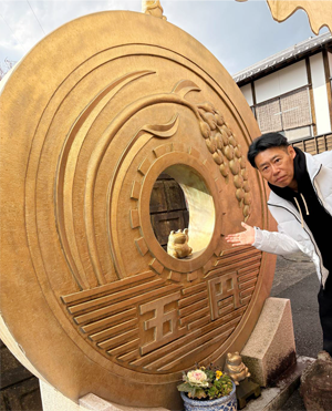 福岡県の如意輪寺（かえる寺）でポーズをとる田中社長の写真